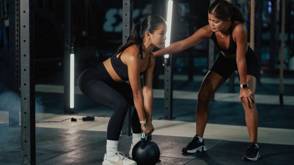 The Benefits of Strength Training in Physical Therapy | A female physical Therapy trainer guides a female athlete on carrying a medicine ball.