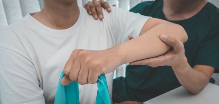 A physical Therapist administering a paitient's arm, closeup image, patient holding a stretching band.