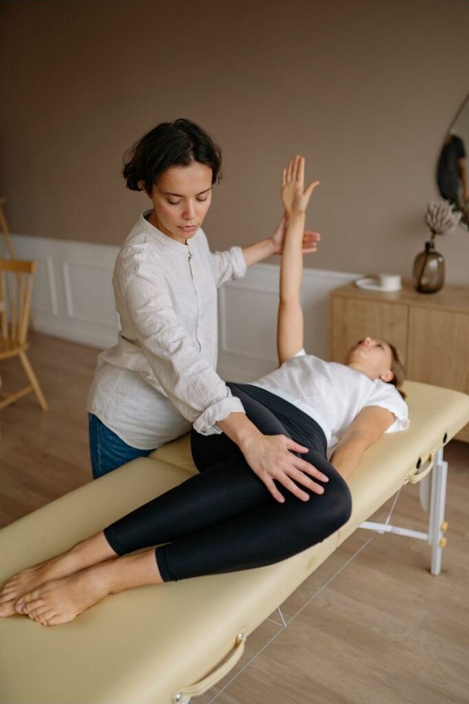A female physiotherapist teaching her patient lying on the table some exercises.