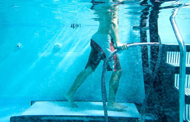 Underwater view of a man doing some aquatic therapy exercises with use of a walking support.