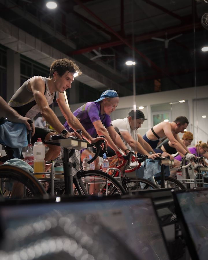 A group of people with different physicality using indoor bicycles during an intense sweating exercise.