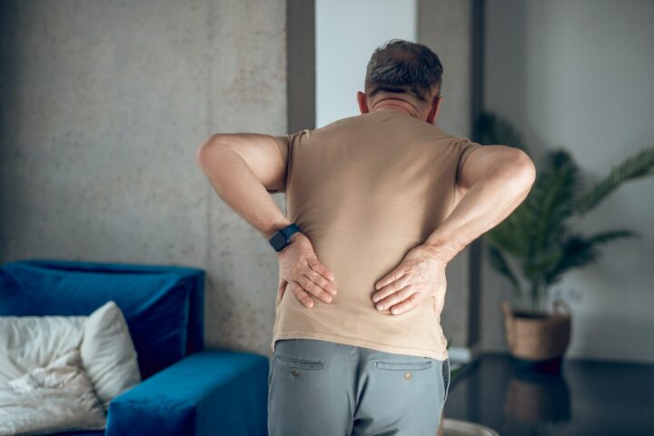 A man having pain in his lower back pictured from the back