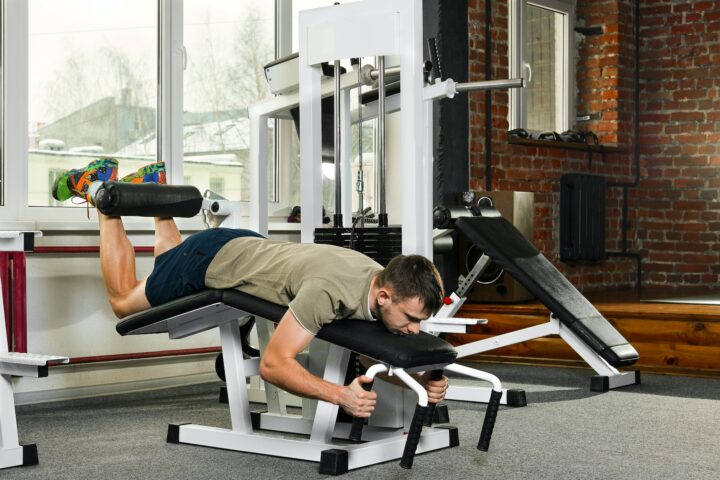 An atheletic man swinging the abdominal muscles in the gym with a machine requiring him to lie face down.