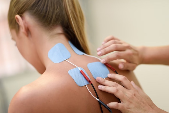 A young woman being treated with electro simulation on her neck during physical therapy.