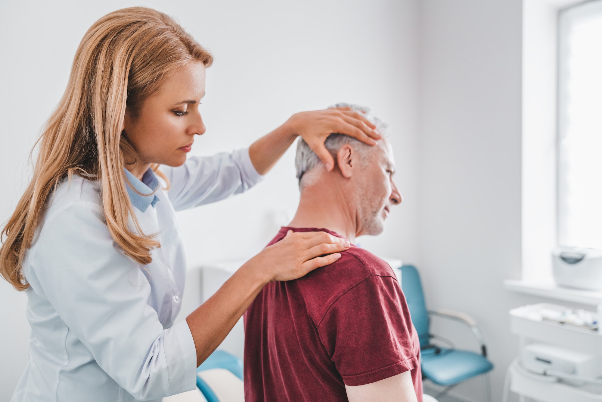 Female orthopedist examining patient's neck in hospital for headache or migraine