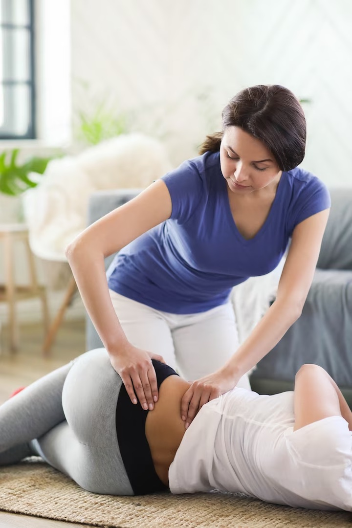 A female physiotherapist in midst of a session with a female patient targeting the hip area.