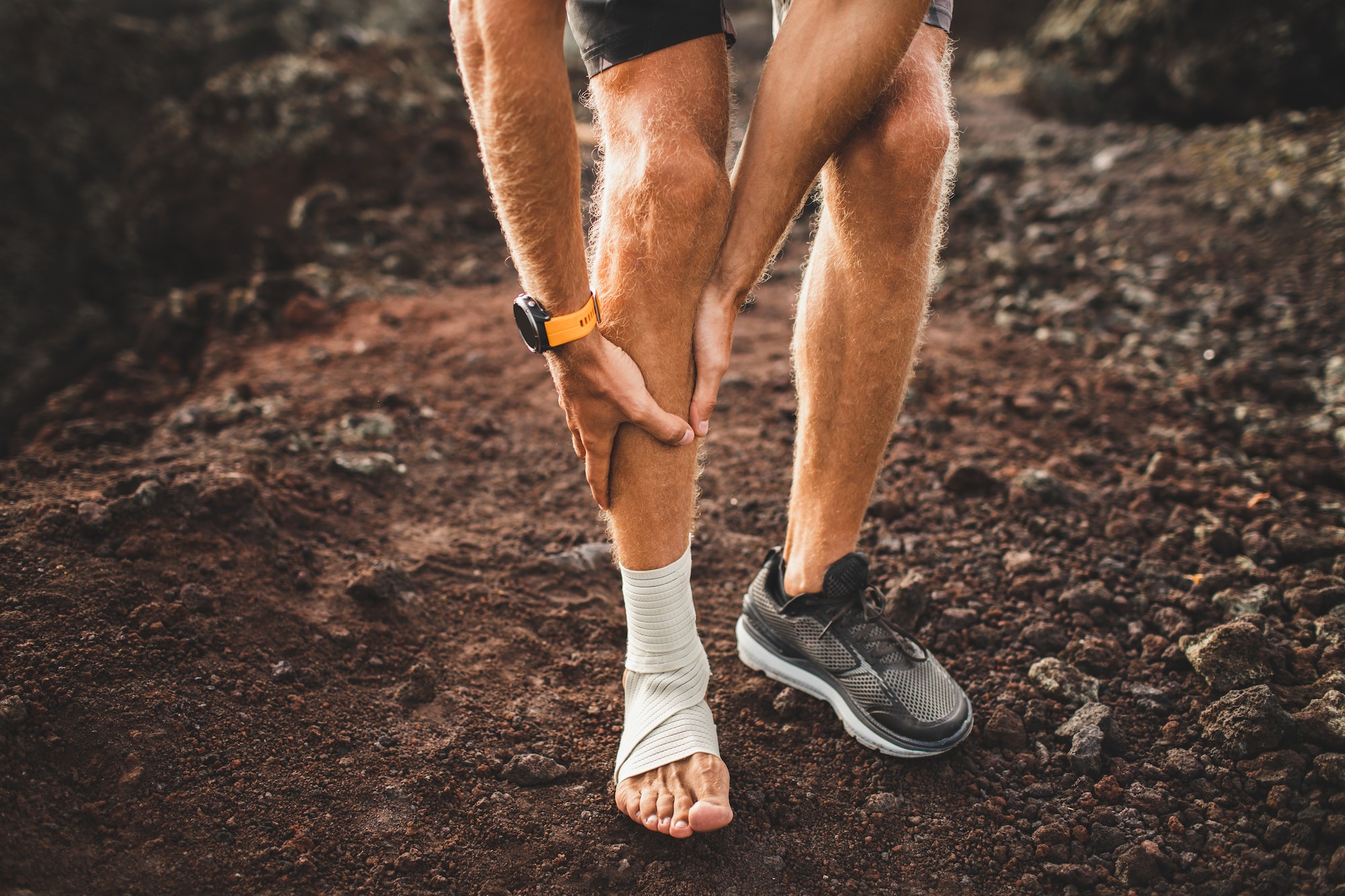 Male runner holding injured leg close-up and suffering achilles tendon.
