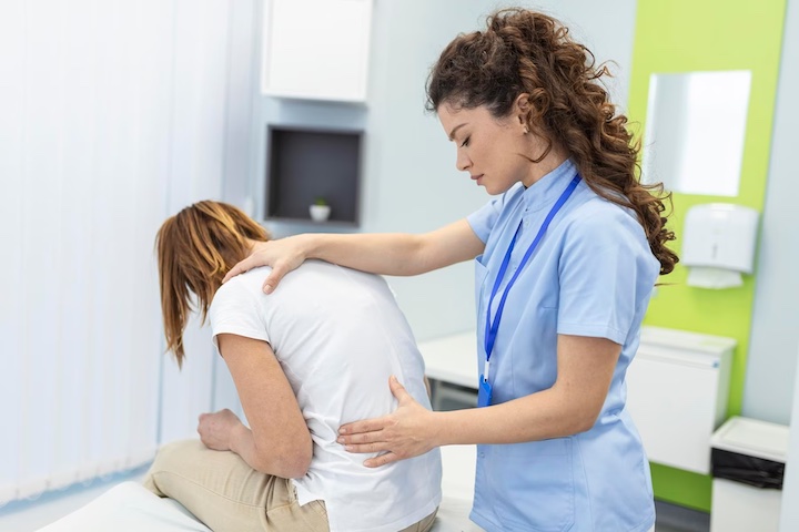 A female physiotherapist treating a female patient with her back pain.
