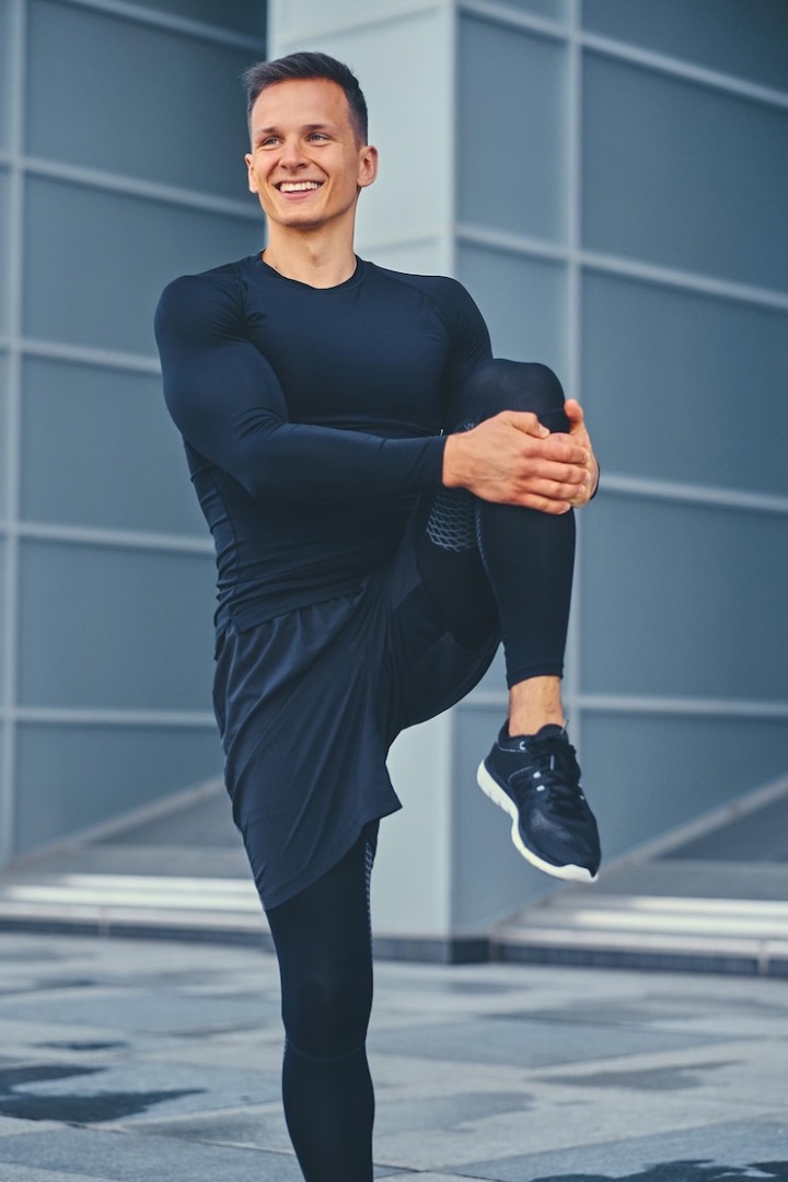 male athlete streatching in front of a modern building