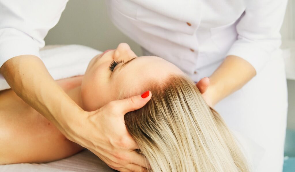 Beautician cosmetologist makes a relaxing head and hair massage in a beauty clinic spa salon