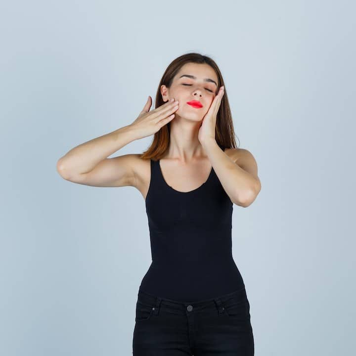 A woman in all black outfit performing jaw exercises to relieve tmj pain.