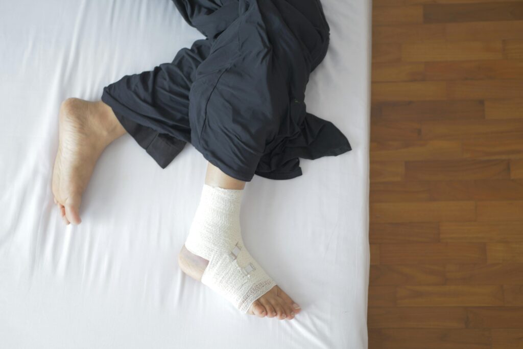 A man resting on a bed with a cast on his leg, highlighting the impact of plantar fasciitis and calf pain.
