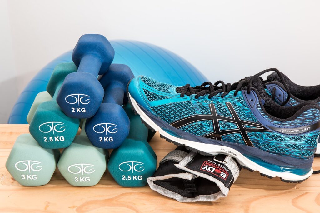 A pair of blue running shoes alongside a single dumbbell and a pair of dumbbells, symbolizing fitness and exercise.