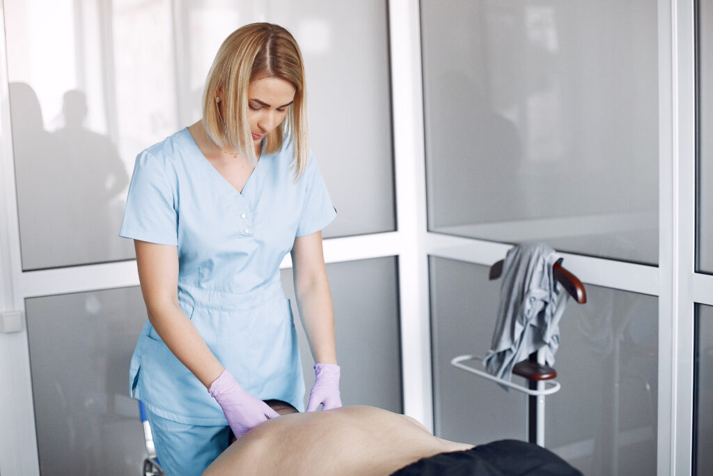 A woman in blue scrubs administers a massage to a man, aiding recovery following dry needling therapy