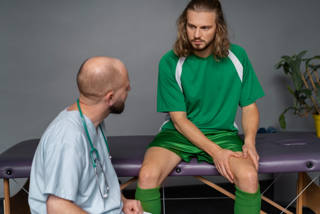 A man consults with a doctor at a table, discussing key symptoms that may require physiotherapy treatment.