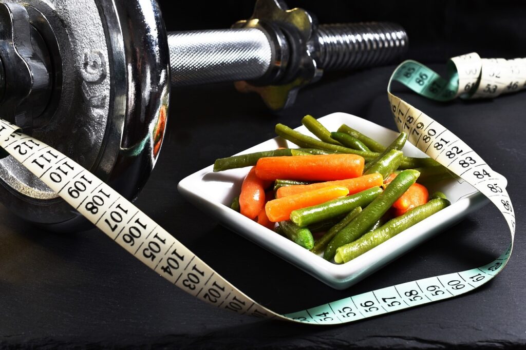 A plate of fresh vegetables beside a measuring tape and a weight scale, symbolizing long-term weight maintenance.