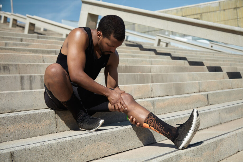 A man sits on building steps, foot on the ground, reflecting on preventive measures and lifestyle adjustments.