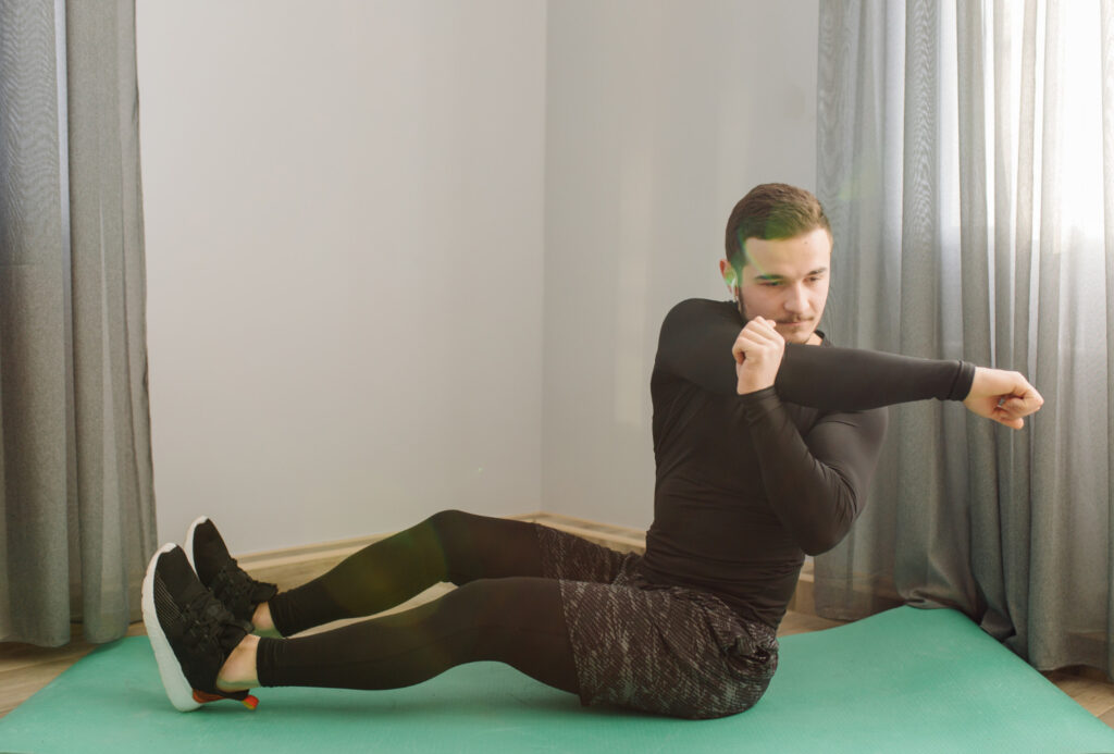 A man performs a sit-up on a green mat, focusing on progressive strengthening exercises for core fitness.