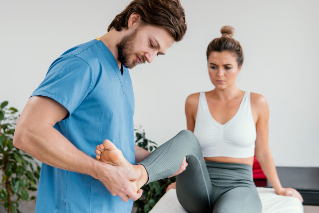 A man and woman consult in a physio room, discussing treatment for plantar fasciitis with a physiotherapist.
