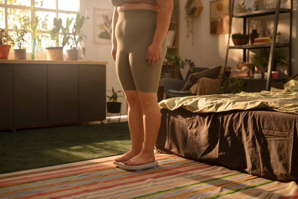 A woman stands on a bed in a room, illustrating symptoms of fat pad impingement.