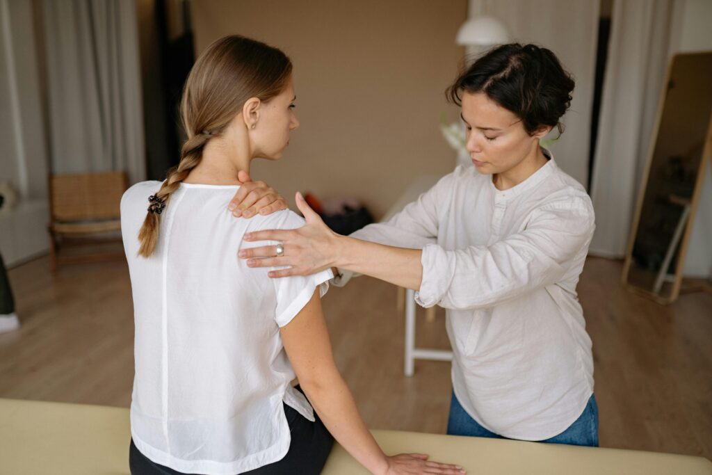 A woman receives a shoulder examination from a physical therapist, addressing symptoms of shoulder bursitis.