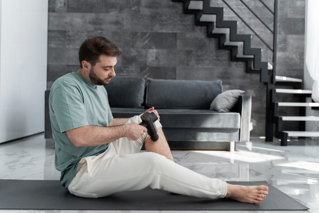 A man sitting on the floor with his legs raised, illustrating a stage in hamstring recovery exercises.