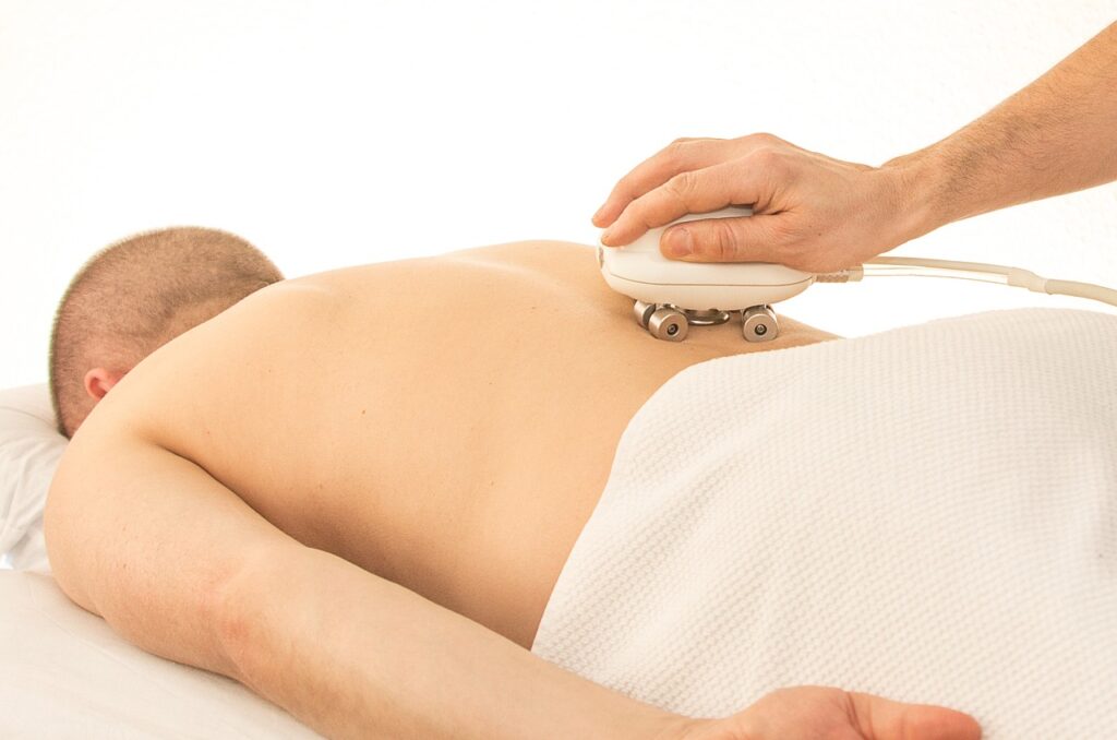 A man using a massage device on his back, highlighting key physiotherapy exercises for alleviating lower back pain.