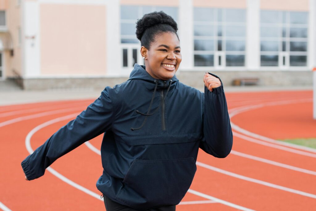 A woman sprinting on a track, showcasing determination and focus as she prepares to return to full activity.