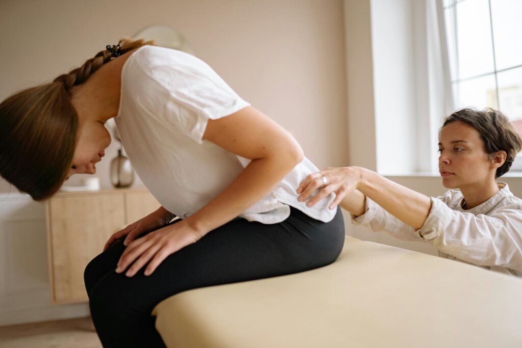 A woman receiving a back examination from a chiropractor, highlighting the importance of seeking physiotherapy care.