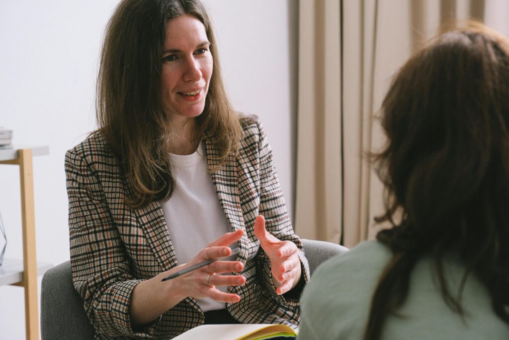 A woman discusses important topics with another woman during a meeting, emphasizing the need for professional guidance.
