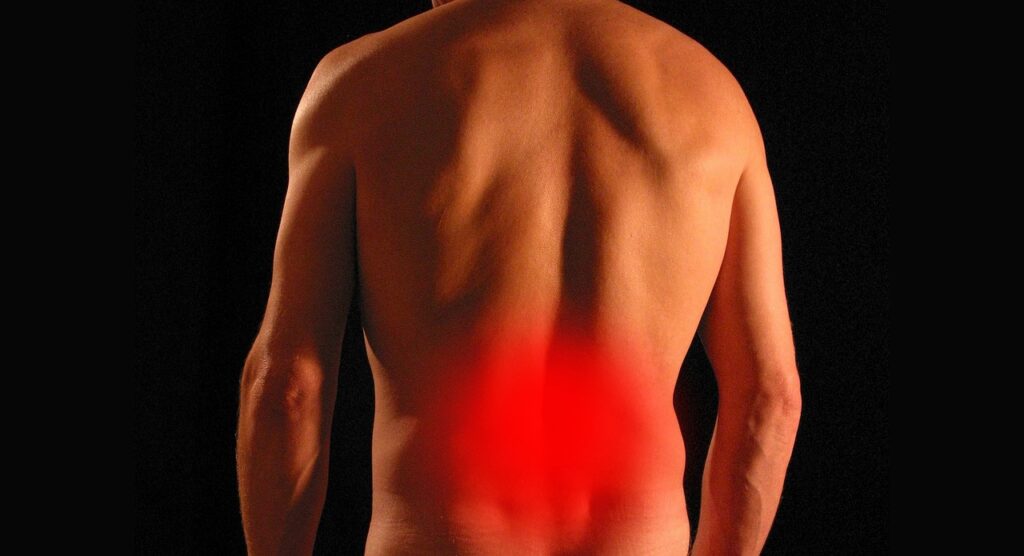 A man holding his lower back, showing signs of discomfort due to red back pain.