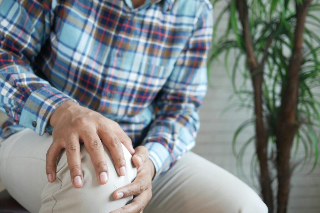 A man experiencing knee pain, holding his knee in discomfort, questioning if shin splints cause knee pain.