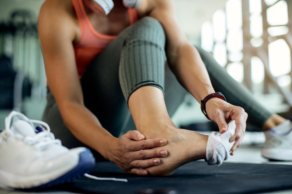 A woman is putting on her shoe, focusing on her foot as she prepares for activity related to ankle pain diagnosis.