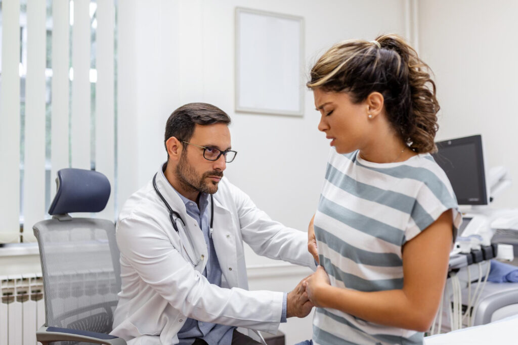 A man carefully examines a woman's stomach, focusing on diagnosing her floating rib pain with a concerned expression.