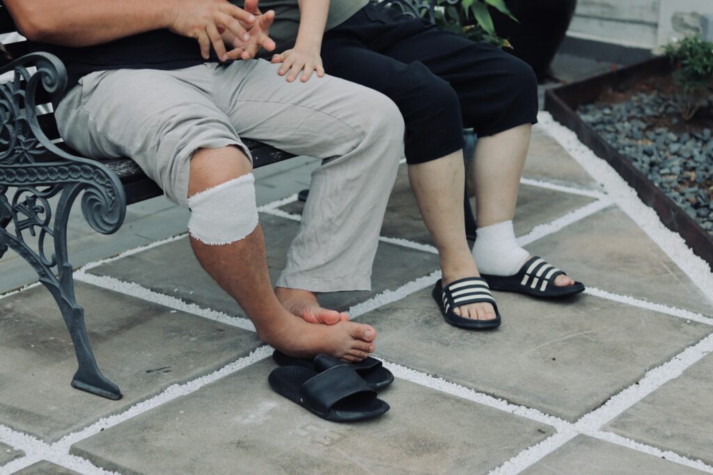 A man and woman relax on a bench, discussing footwear choices for recovery after an injury or surgery.
