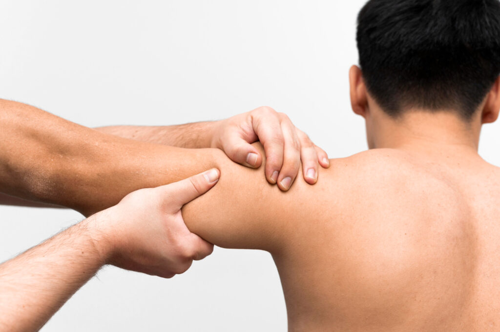 A man receives a shoulder massage from another man, focusing on key acupressure points for shoulder pain relief.