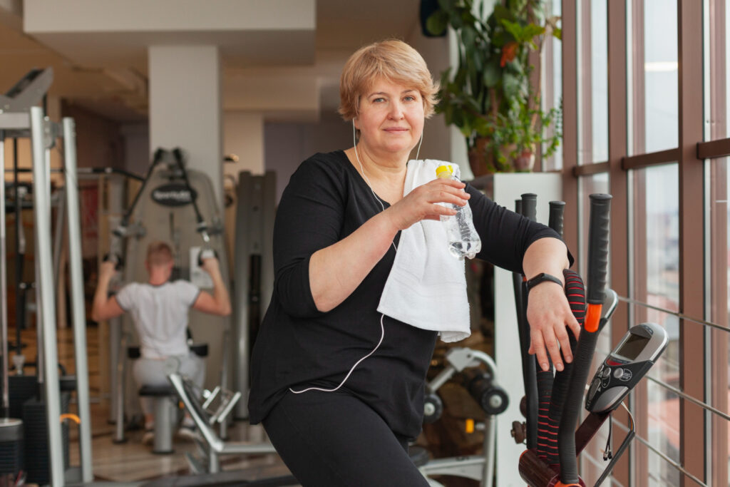 A woman focused on her workout, pedaling on a stationary bike in a vibrant gym setting, embodying fitness and determination.