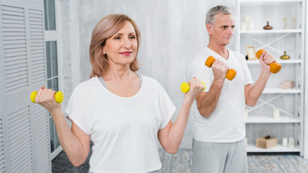 An older couple engaged in dumbbell exercises, promoting long-term health and fitness in a cozy room setting.