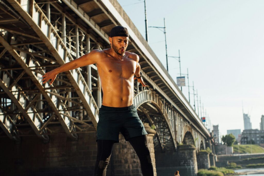 A shirtless man jumps on a skateboard, showcasing athleticism and freedom of movement while preventing iliacus muscle tightness.
