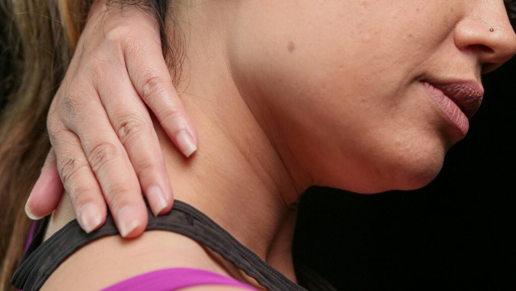 A woman gently holds her neck, symbolizing care and prevention of wry neck recurrence.