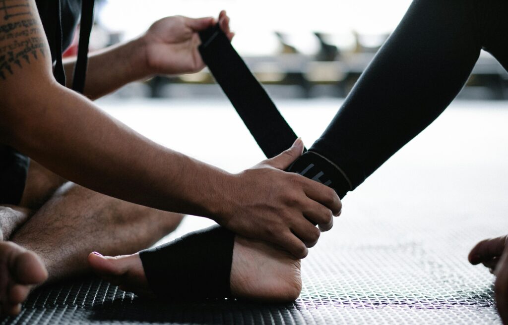 A person wraps a bandage around another's foot, demonstrating ankle health management and injury prevention techniques.