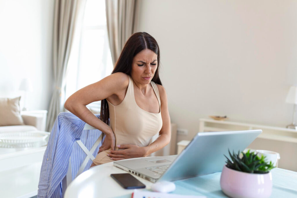 A woman practices self-care at her desk, focusing on pain management strategies while seated with her back to the camera.