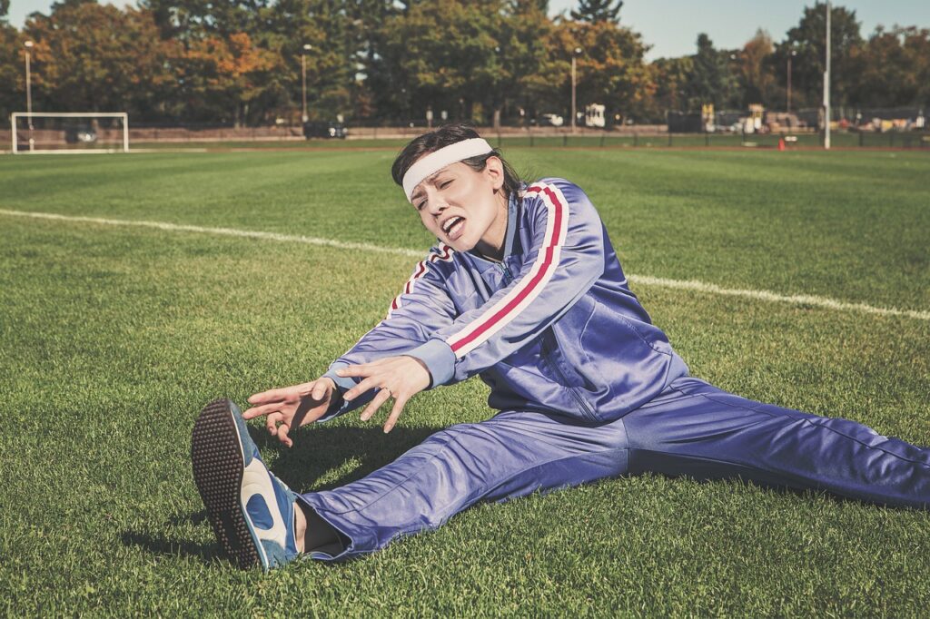  A woman stretches on the grass, demonstrating a relaxing exercise routine in a natural setting.