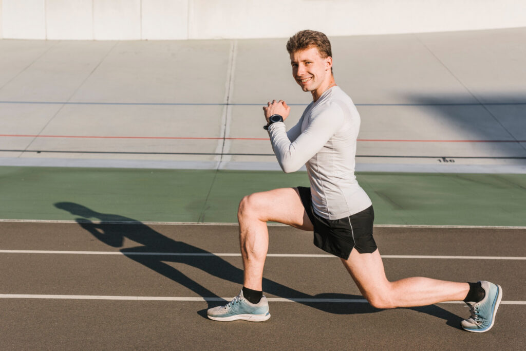 A man stretches on a running track, demonstrating safe stretching techniques to enhance flexibility and prevent injury.