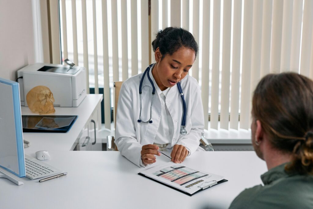 A woman doctor consults with a man in her office, discussing when to seek further medical advice for his health concerns.